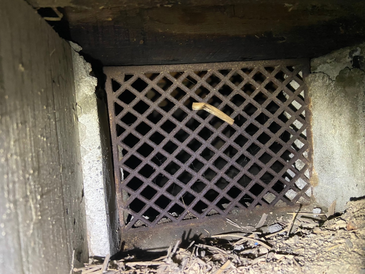 甲賀市の住宅の床下側から見た錆びた格子の通風口。すき間から動物が出入りできる封鎖前の状態